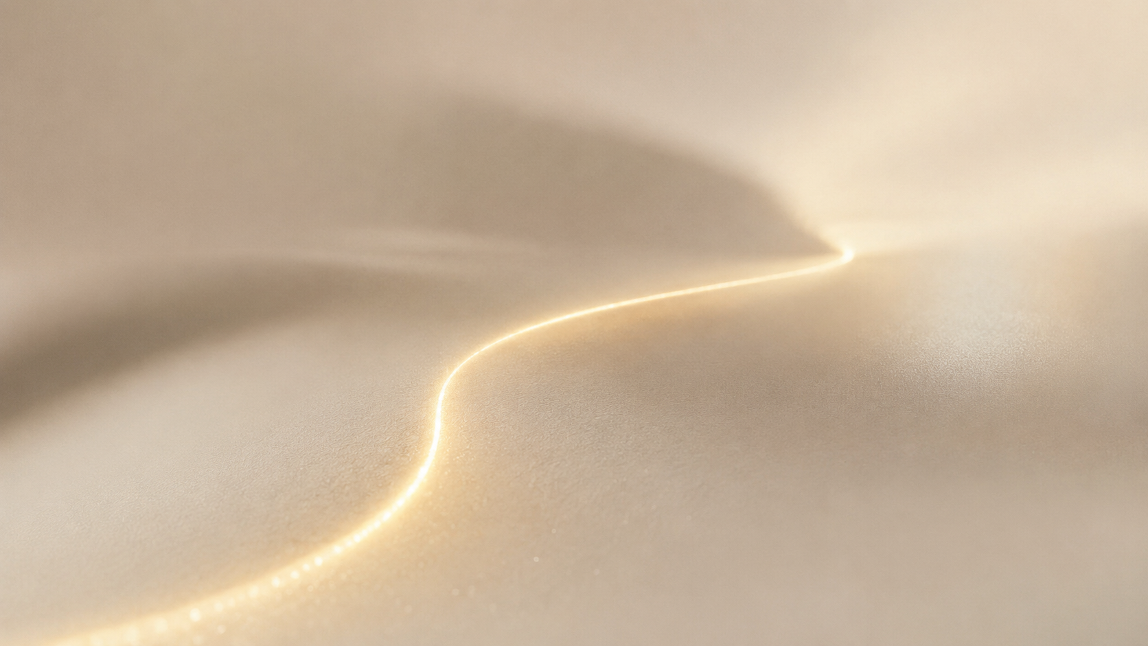 A single line of warm light settling across a soft cream surface